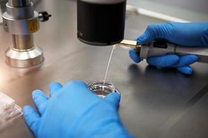 Hands of a scientist in the laboratory with a test tube and a microscope. The invention of the vaccine, a doctor in the clinic of artificial insemination IVF. Tests, fertilization of the egg photo