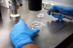 Hands of a scientist in the laboratory with a test tube and a microscope. The invention of the vaccine, a doctor in the clinic of artificial insemination IVF. Tests, fertilization of the egg photo