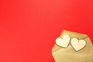 Wooden hearts spill out of an open envelope on a red background. Valentine's Day, love letter, declaration of love, acquaintance. Copy space, mock up photo