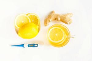 Medicinal tea in cup, ginger, lemon-strengthen immune system in the cold season. Vitamin drink for health and ingredients, thermometer on a white background. Flu, cold, immunity, fever, antipyretic photo