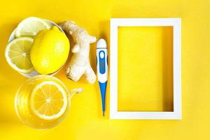 Medicinal tea in a cup, ginger, lemon-strengthen the immune system in the cold season, thermometer and copy space, sheet for notes. Vitamin drink for health and ingredients on yellow background. photo