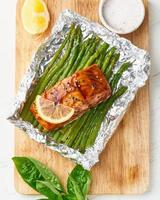 cena de paquete de aluminio con pescado rojo. filete de salmón con espárragos. cena caliente al horno foto