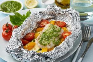 cena de paquete de aluminio con pescado blanco. lomo de bacalao al horno, lucioperca con verduras foto