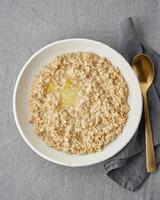 Whole oatmeal, large bowl of porridge with butter for breakfast, morning meal. Top view photo