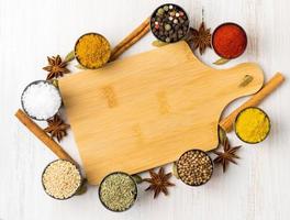 Various Indian spices in metal cups. Empty wooden Board, seasoning on white wooden table. top view, space for text. photo