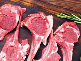 Raw lamb cutlets on bone on dark brown wooden background, lamb ribs, top view. photo