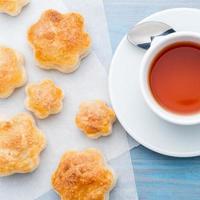 traditional breakfast with a cup of tea and sweet pastries - scones, a mug of tea, spoon, on wooden blue table, top view. photo