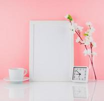 Blank white frame, flower, clock and cup of coffee or tea on whi photo