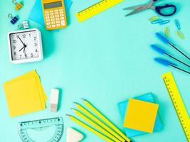 Top view of modern bright blue office desktop with school supplies on table around empty space for text. Back to school concept. photo