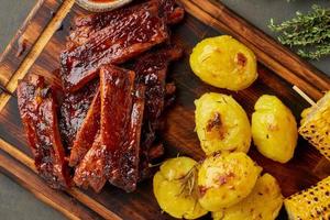 Spicy barbecue pork ribs, corn ears and crushed smashed potatoes. Slow cooking recipe. photo
