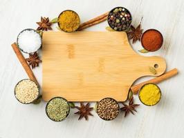 Various Indian spices in metal cups. Empty wooden Board, seasoning on white wooden table. top view, space for text. photo