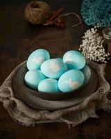 Unusual Easter on dark background. Ceramic brown bowl with blue eggs. Darkness, rays of sunlight photo