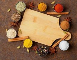 Various Indian spices in metal cups. Empty wooden Board, top view, space for text. photo