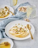 Ricotta with pears, pistachios and honey or maple syrup on white plate