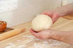 Faceless man kneading dough on kitchen table at home, apartment, flour, scales photo