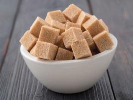 brown cane sugar in a white Cup on a brown wooden background, side view photo