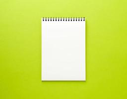 Blank notepad white page on green desk, color background. Top view, empty space for text. photo