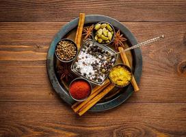 Oriental spice set - coriander, red pepper, turmeric, cinnamon, star anise, various seasonings in metall plate, on brown dark wooden table, top view, macro photo