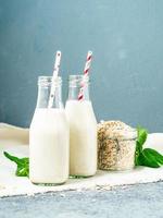 Smoothie with oatmeal, mint for healthy breakfast. Oat milk in glass bottle with tube on dark stone background. photo