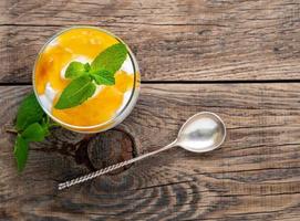Healthy layered dessert with yogurt, banana, mango , cracker on wooden background, top view. photo