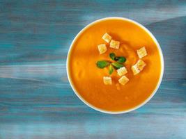 big bowl of pumpkin soup on a wooden blue background. Bright tasty dish, top view photo