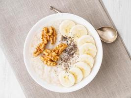 healthy breakfast - oatmeal with nuts, bananas, chia, top view photo