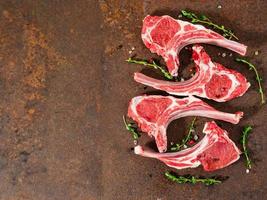 raw lamb cutlets on bone on dark metallic background, top view, empty space. photo