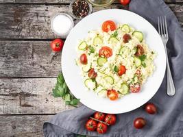 fresh diet vegetable salad with couscous, tomatoes, cucumbers, parsley, dark rustic wooden table, top view, copy space photo