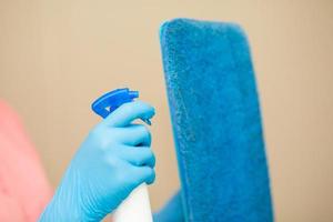 persona, una mano en un guante de goma azul en la foto, quita y lava el lavabo del baño foto