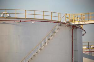 large Industrial tanks for petrol and oil with blue sky.Fuel tanks at the tank farm. metal stairs on the side of an industrial oil container. Staircase on big fuel tank photo