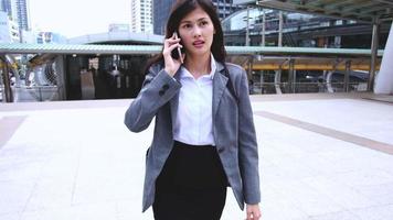 Portrait of young Asian businesswoman on cellphone running while talking on smart phone in urban. Hurrying to the work to office. video