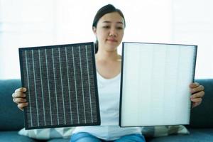 Asian young woman showing an used and the new air purifier filer, comparing between used dirty and new air filter. photo