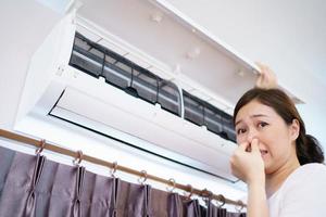 Asian woman cleaning a dirty and dusty air conditioning filter in her house. Housewife removing a dusty air conditioner filter. photo