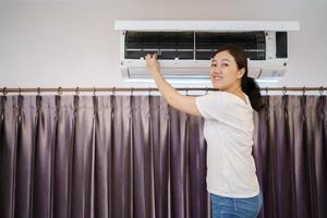 mujer asiática limpiando un filtro de aire acondicionado sucio y polvoriento en su casa. ama de casa quitando un filtro de aire acondicionado polvoriento. foto