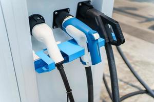 Modern electric vehicle charging connector plugs at ev charging station. DC or direct current and AC or alternating current charging connectors for EV car. photo
