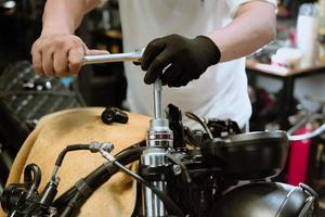 Mechanic using a wrench and socket on motorcycle in garage .maintenance,repair motorcycle concept .selective focus photo