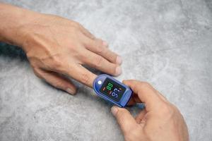 man using pulse oximeter device on finger,Oxygen Saturation Monitor use light pass through the blood in finger measuring amount of oxygen,healthcare concept, photo