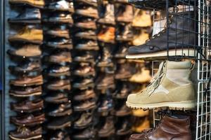 zapatos de segunda mano en exhibición en los estantes, frente a la zapatería en el mercado de fin de semana de chatuchak, bangkok. foto