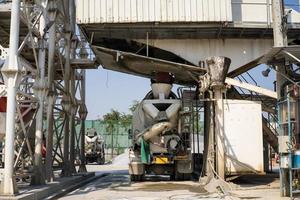 camiones mezcladores de hormigón esperando para cargar la mezcla de hormigón en la fábrica de dosificación para ir al lugar de fundición en el sitio de construcción. foto