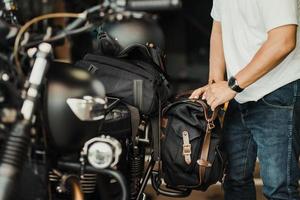 rider install a motorcycle saddlebag or side bag on luggage bracket  vintage motorbike. motorcycle travel concept. selective focus photo