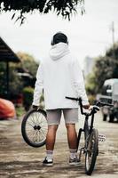 maqueta de sudadera con capucha de vista trasera de un hombre de pie con su bicicleta foto