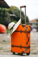 Close up of orange vintage suitcase with summer hat for travel or holiday concept photo