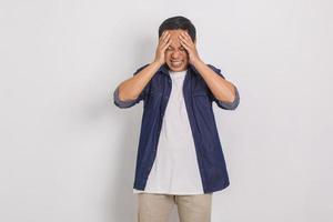 retrato de un apuesto hombre asiático mareado mientras sostenía la cabeza con ambas manos aislado en fondo blanco foto