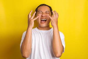 Close-up portrait of Asian man screaming, get surprised isolated on yellow background photo