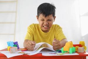 rabieta emocional y niño enojado mientras dibuja en papel. experiencia traumática infantil, psicología psicológica, síndrome de asperger, trastorno de asperger, autista, autismo. foto
