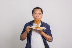 hombre asiático comiendo muchos fideos instantáneos y se sorprende con lo delicioso que es foto