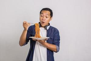 hombre asiático comiendo fideos instantáneos y se sorprende con lo delicioso que es foto