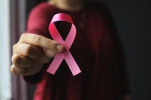 mano que sostiene la cinta rosa para el día mundial del cáncer y la concienciación sobre el cáncer de mama foto