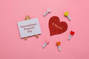 composición plana del día internacional de la mujer en el cartel, 8 de marzo en corazones rojos brillantes y mini corazones sobre fondo rosa foto
