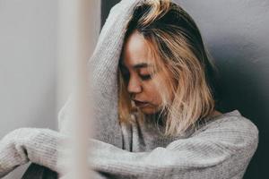 Depressed and sad young woman sitting alone at home photo